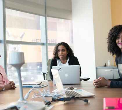 photography of three women sits beside table inside room during daytime
